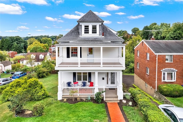 view of front facade featuring a balcony, a front yard, and a porch