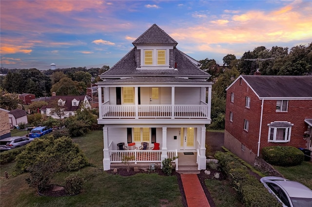 view of front of property featuring a yard, a porch, and a balcony