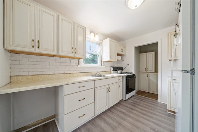 kitchen featuring light hardwood / wood-style flooring, decorative backsplash, white gas stove, and sink