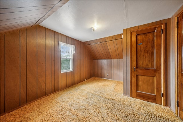 additional living space with wooden walls, vaulted ceiling, and carpet floors