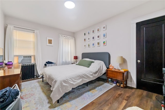 bedroom featuring radiator heating unit and hardwood / wood-style flooring