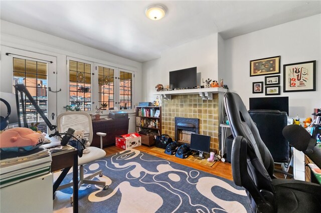 office area featuring hardwood / wood-style flooring, a tiled fireplace, french doors, and a wealth of natural light