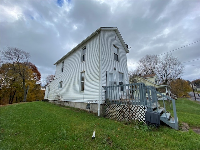 back of property featuring a deck and a lawn