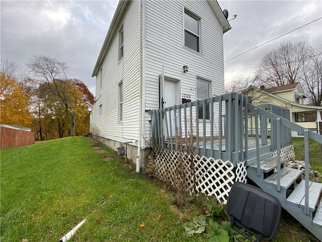 rear view of property with a wooden deck and a yard