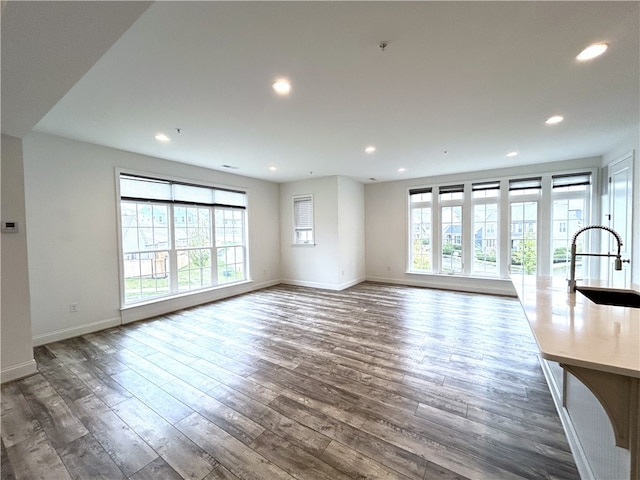 unfurnished living room featuring dark hardwood / wood-style flooring, plenty of natural light, and sink