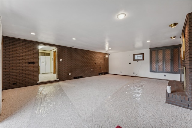 unfurnished living room with carpet flooring and brick wall