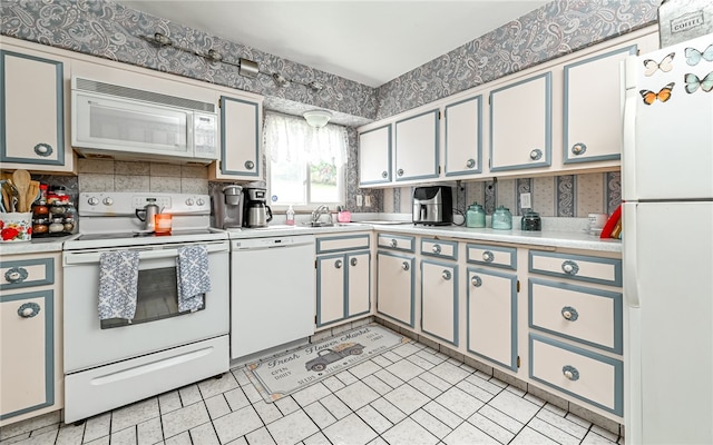 kitchen featuring white appliances, light tile patterned floors, and sink