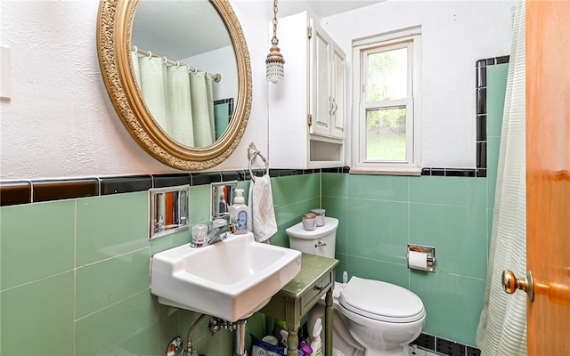 bathroom featuring toilet, a shower with curtain, sink, and tile walls