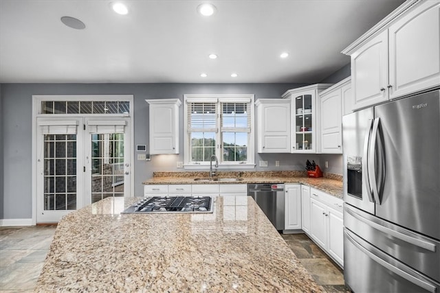 kitchen featuring light stone counters, appliances with stainless steel finishes, sink, and white cabinetry