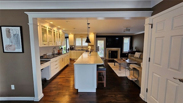 kitchen with tasteful backsplash, white cabinets, a breakfast bar area, ornamental molding, and dark hardwood / wood-style floors