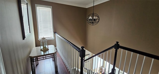 staircase with ornamental molding and an inviting chandelier