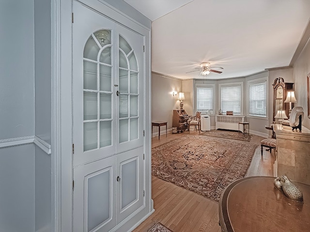 interior space featuring ceiling fan, light hardwood / wood-style flooring, ornamental molding, and radiator heating unit