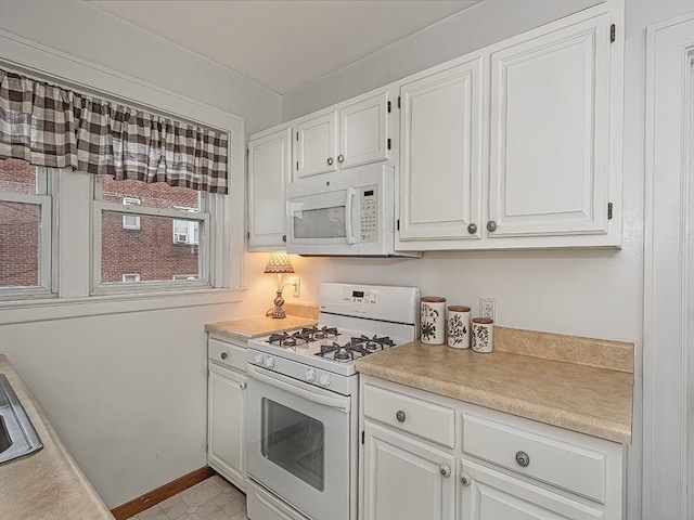 kitchen featuring white appliances, white cabinetry, and sink