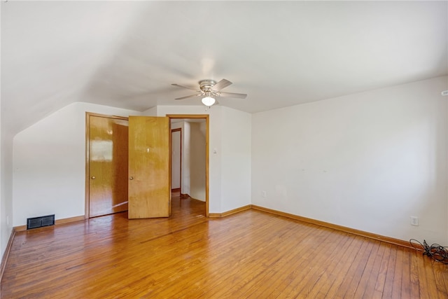 empty room with ceiling fan, vaulted ceiling, and hardwood / wood-style floors