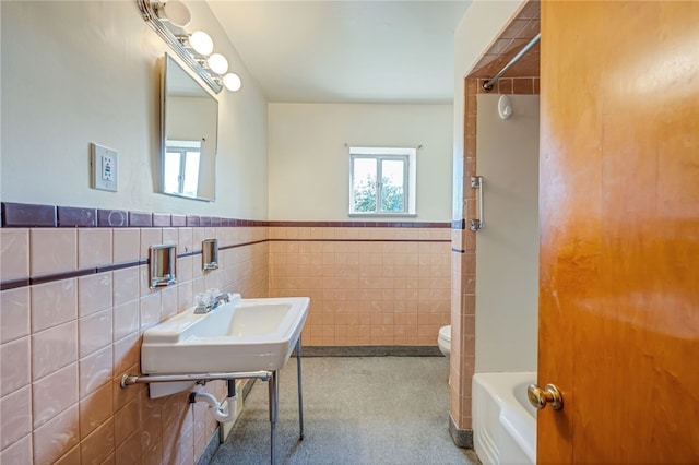 bathroom with tile walls, bathtub / shower combination, and toilet