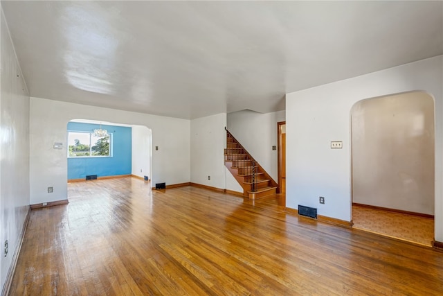 unfurnished living room with a chandelier and wood-type flooring