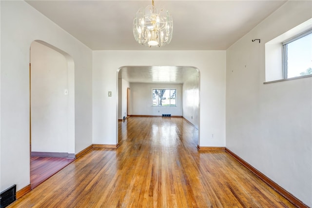 empty room featuring hardwood / wood-style flooring and a chandelier