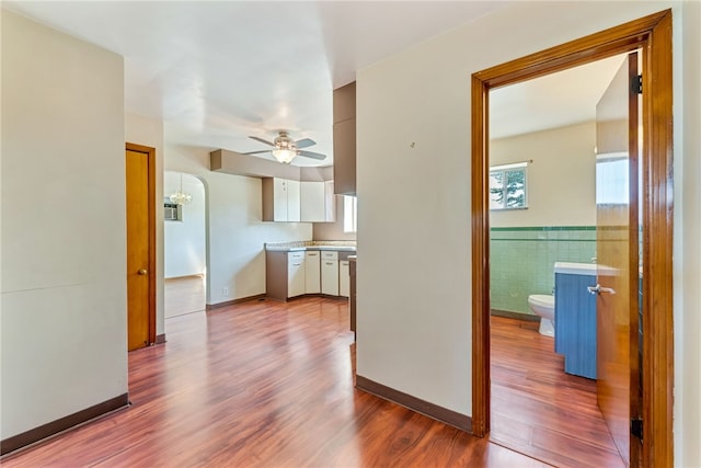 kitchen with wood-type flooring, white cabinets, tile walls, and ceiling fan