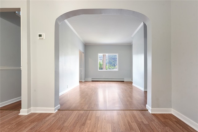 spare room featuring a baseboard radiator, hardwood / wood-style floors, and crown molding