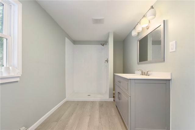 bathroom with hardwood / wood-style floors, a shower, and vanity