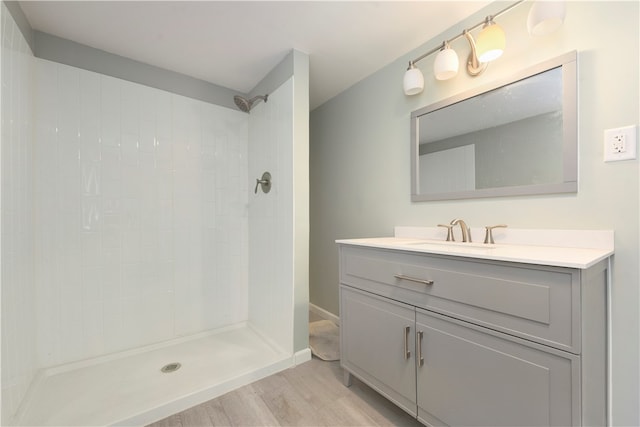 bathroom with wood-type flooring, vanity, and a tile shower