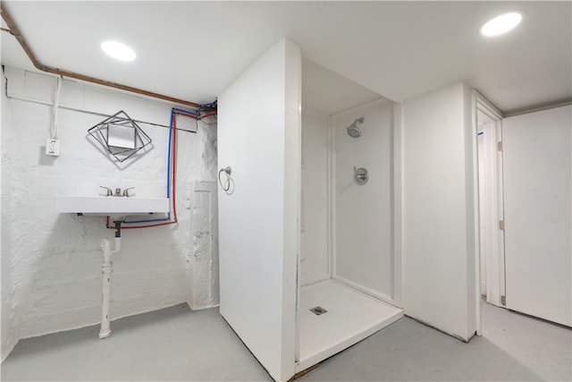 bathroom with concrete floors, walk in shower, and sink