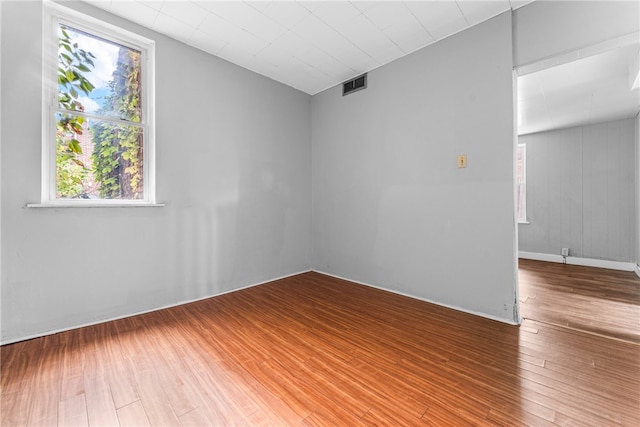 unfurnished room featuring wooden walls and hardwood / wood-style floors