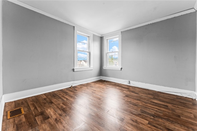 empty room with dark hardwood / wood-style floors and crown molding