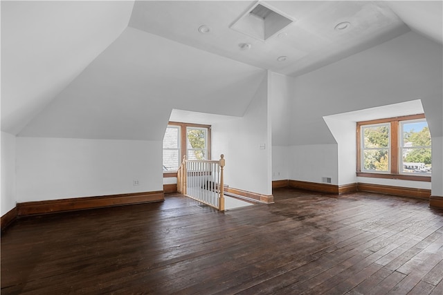 additional living space featuring vaulted ceiling, dark wood-type flooring, and a wealth of natural light