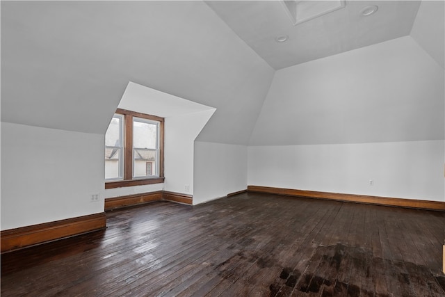 additional living space featuring vaulted ceiling and dark hardwood / wood-style flooring