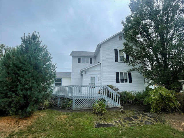 rear view of house with a wooden deck and a lawn