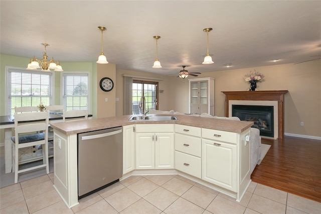 kitchen with sink, stainless steel dishwasher, a kitchen island with sink, ceiling fan with notable chandelier, and a wealth of natural light