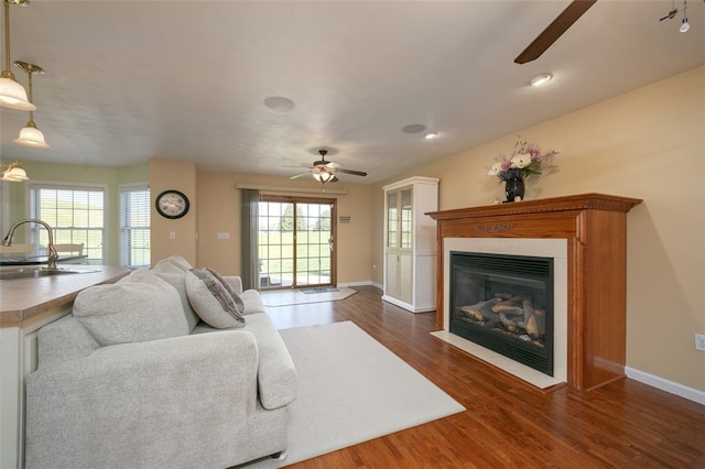 living room featuring ceiling fan, sink, and dark hardwood / wood-style flooring