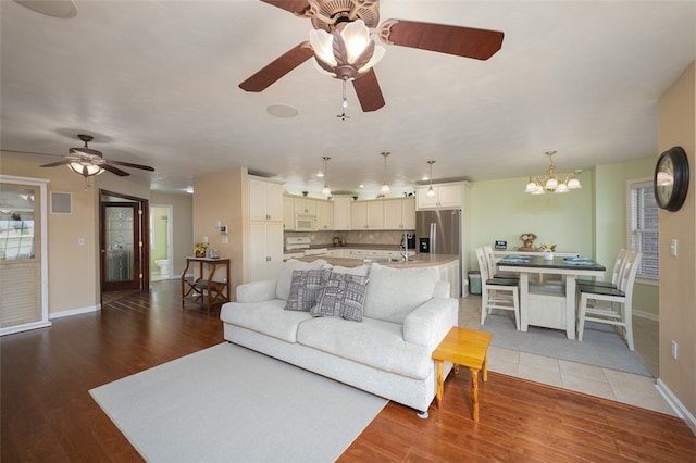 living room with ceiling fan with notable chandelier, hardwood / wood-style floors, and sink