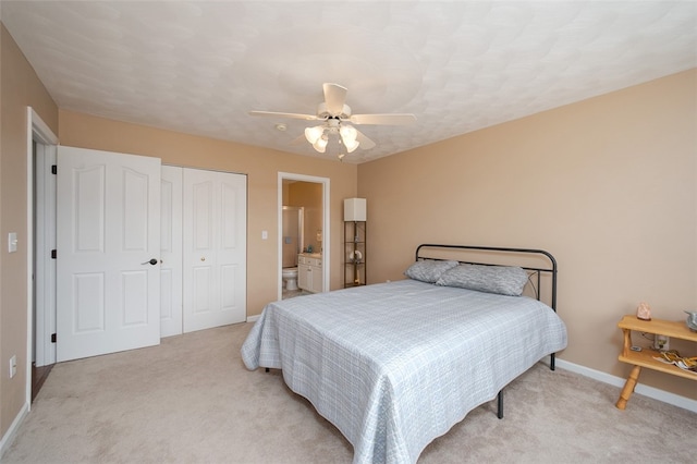 bedroom featuring light carpet, ceiling fan, ensuite bathroom, and a closet