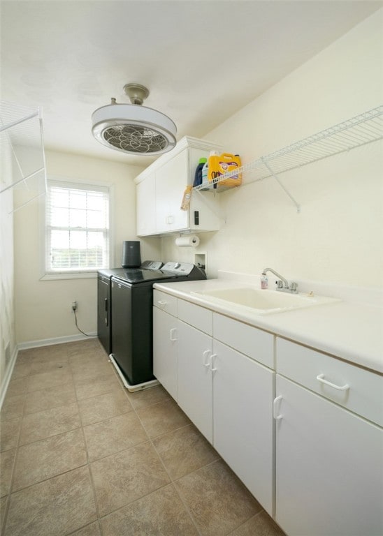 laundry area featuring washing machine and dryer, sink, light tile patterned floors, and cabinets