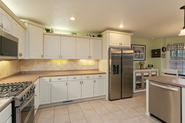 kitchen featuring backsplash, light tile patterned floors, appliances with stainless steel finishes, and decorative light fixtures