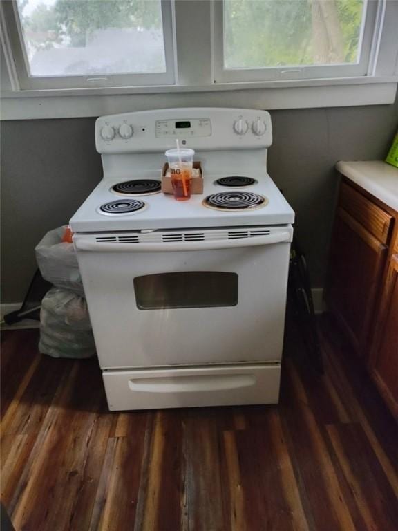 kitchen with a wealth of natural light, white cabinets, dark hardwood / wood-style flooring, and white range with electric cooktop