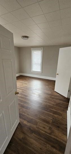 unfurnished room with a drop ceiling and dark hardwood / wood-style floors