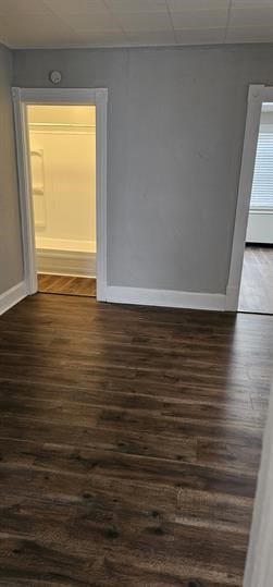 empty room with a paneled ceiling and dark hardwood / wood-style flooring