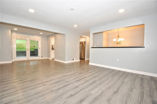 unfurnished living room featuring a chandelier and hardwood / wood-style flooring