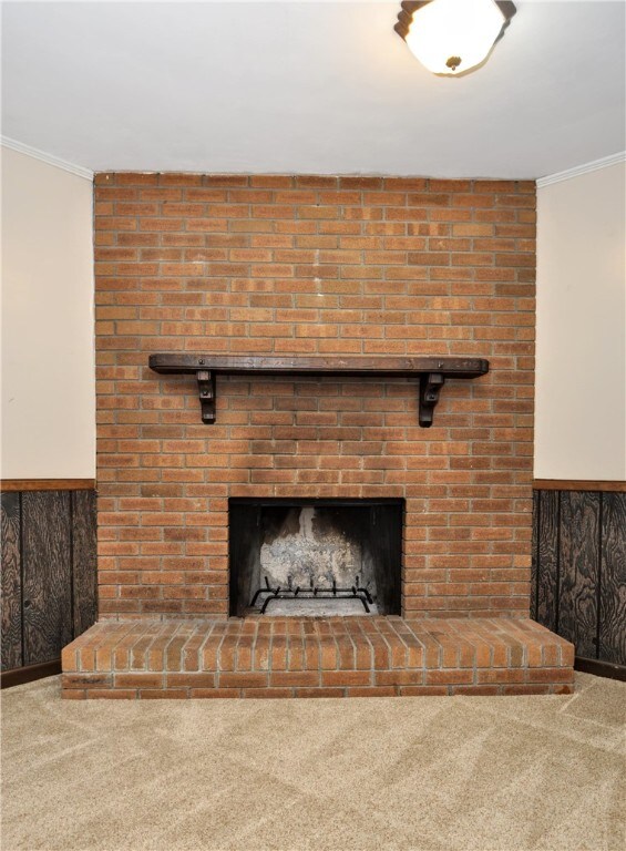 room details with a fireplace, wood walls, ornamental molding, and carpet