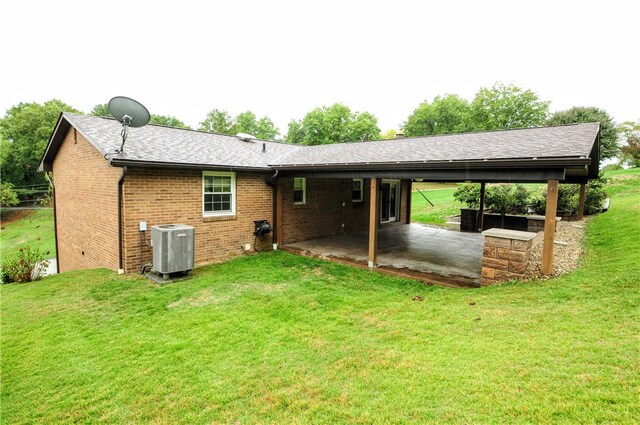 back of property with a lawn, a patio area, and central AC