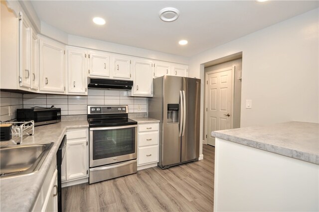 kitchen with light hardwood / wood-style floors, sink, white cabinets, decorative backsplash, and appliances with stainless steel finishes