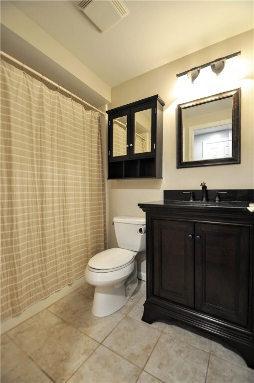 bathroom with vanity, toilet, a shower with shower curtain, and tile patterned floors