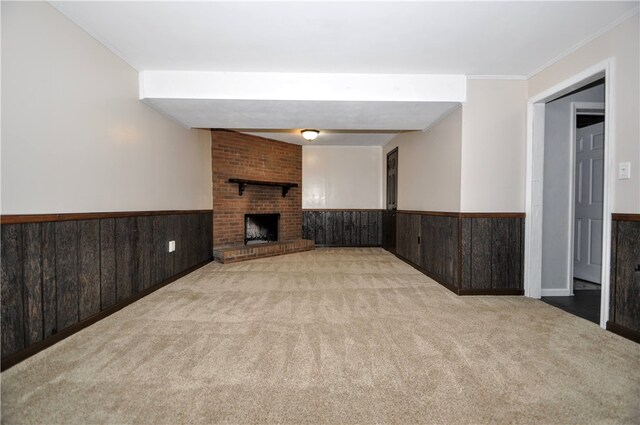 unfurnished living room with ornamental molding, a brick fireplace, wood walls, and light colored carpet