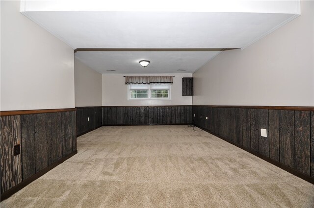 unfurnished room with light carpet, wood walls, and crown molding