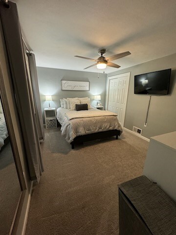 carpeted bedroom with ceiling fan and a closet