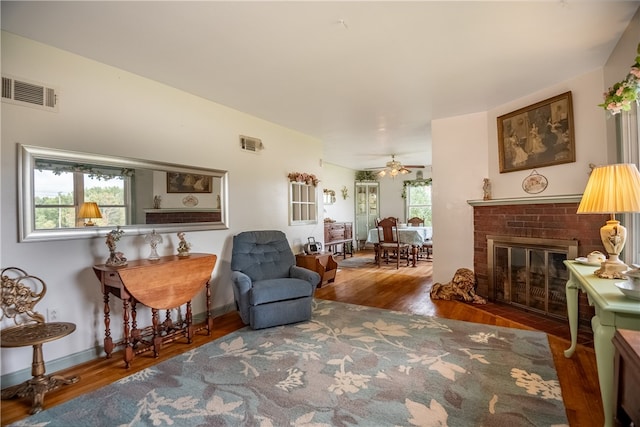 living room featuring hardwood / wood-style floors, ceiling fan, and a fireplace