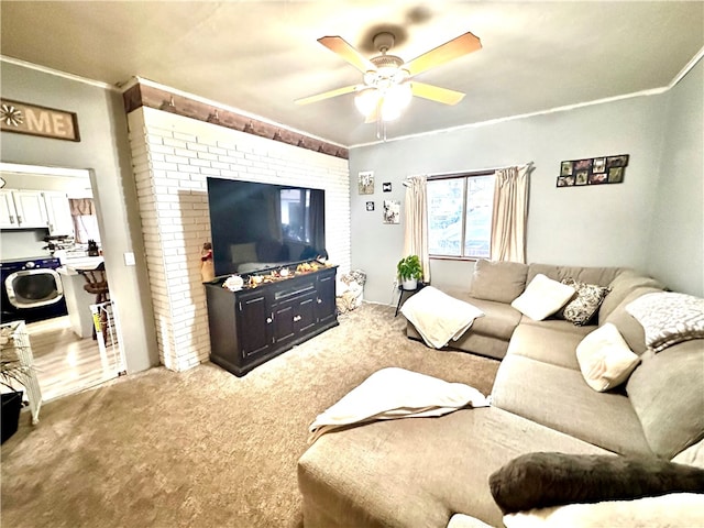 living room with carpet floors, washer / clothes dryer, ornamental molding, and ceiling fan